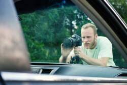 Man taking picture of car window