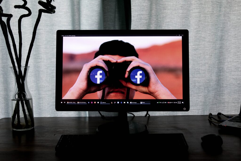 television showing man using binoculars with facebook logos meaning big techs invading our privacy